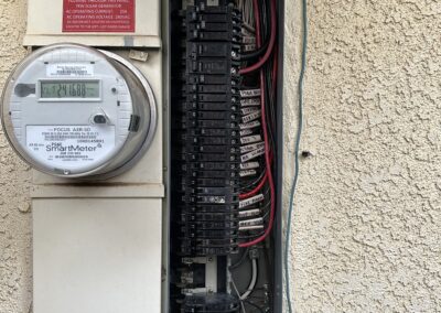 Open electrical panel on a beige wall with a smart meter and multiple circuit breakers, along with a warning label.