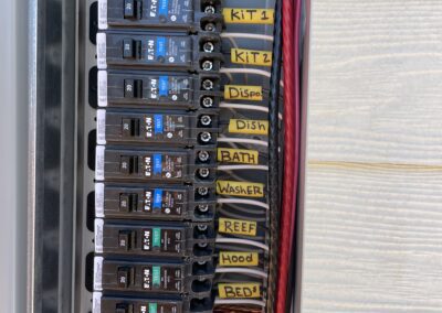 Electrical panel with labeled circuit breakers, including A/C, kitchen, disposal, bath, washer, refrigerator, hood, and bedroom.