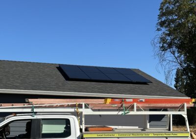 A utility truck parked beside a building with solar panels on the roof against a clear blue sky.